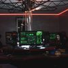 Hakerzy w maskach przy wielu monitorach symbolizujący cyberatak i wyciek danych z sieci Żabka